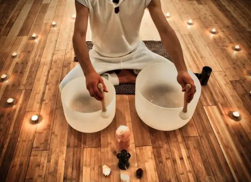 young,man,playing,crystal,bowls,as,part,of,a,meditative